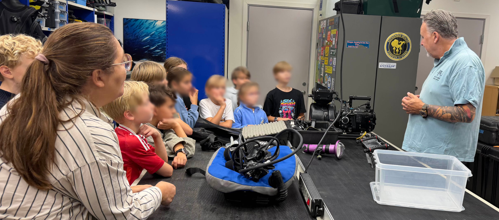 Robert Westerberg shows the students film equipment and diving gear — and the children got to try a diving mask and breathe through a regulator.
