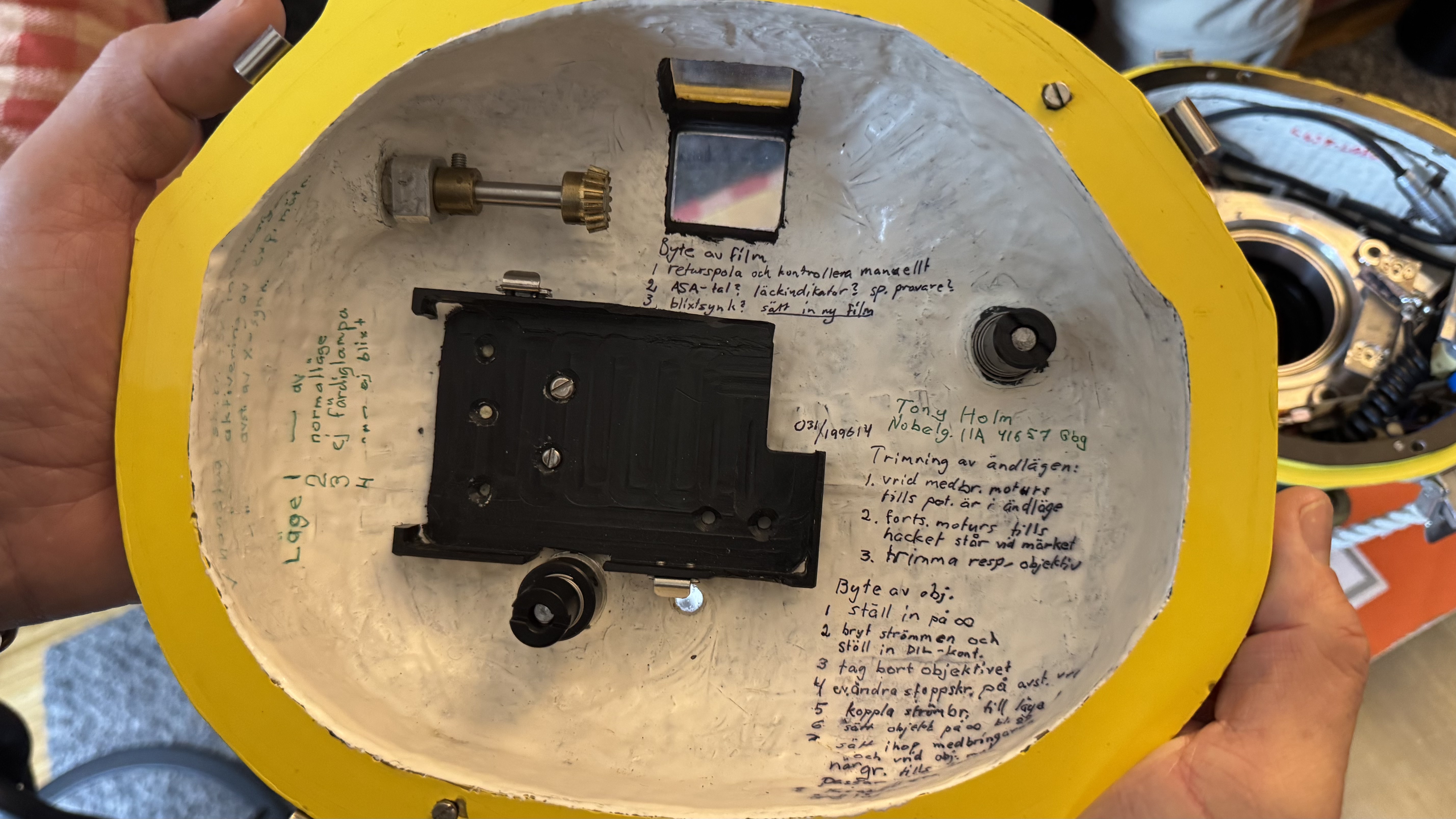 Inside one of Tony Holm's hand-built housings: mechanical linkages, a viewfinder mirror and hand-written operating notes — a working notebook engineered directly into the equipment.