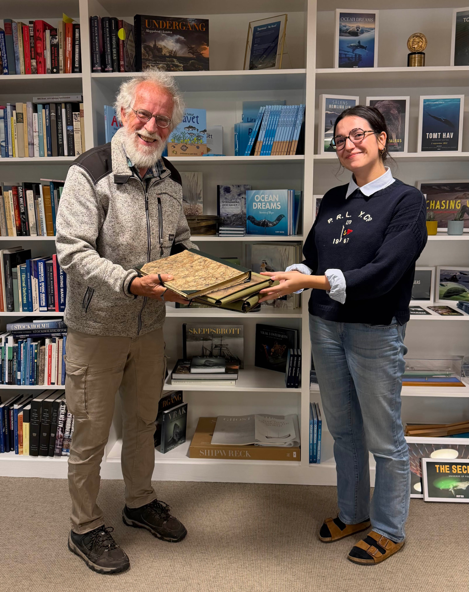 Nils Kautsky hands historic herbarium volumes to an Ocean Archive archivist
